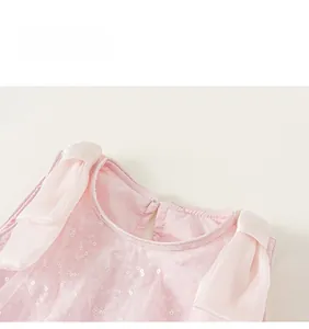 Dettaglio dello scollo dell'abito rosa da bambina con rete di paillettes e fiocco decorativo
