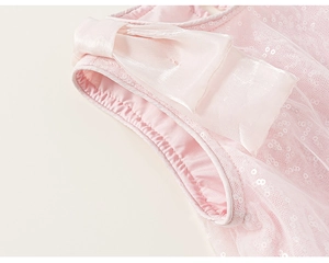 Dettaglio in tulle rosa con paillettes e fiocco di raso su un abito da bambina