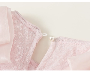 Dettaglio abito in tulle rosa con paillettes e chiusura con bottone a perla sul retro