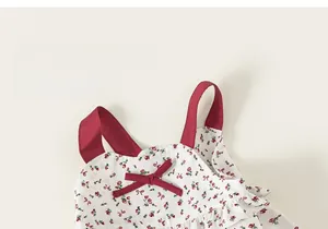 Detail of floral cotton dress featuring a red bow and wide red shoulder straps