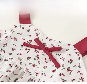 Detail of red bow decoration and floral print on white cotton girl's summer outfit