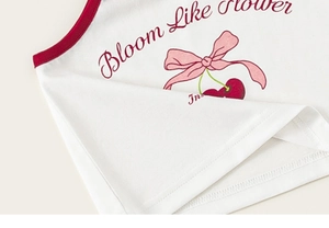 Détail d'un débardeur blanc en coton avec bordure rouge et imprimé cerise doux
