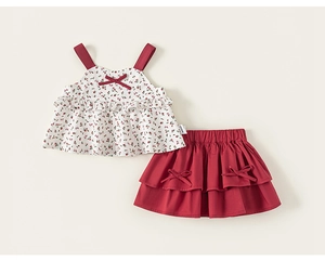 Detailed close-up of floral camisole top and red pleated skirt set with bow accents