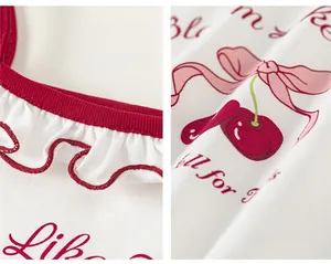 Détail d'un haut pour filles avec motif cerise et col en dentelle à volants rouges