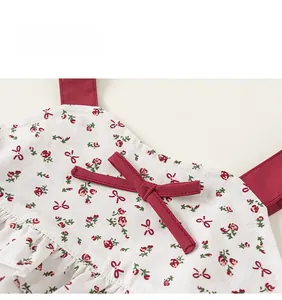 Close-up of floral girls' summer outfit featuring red bow detail and delicate straps