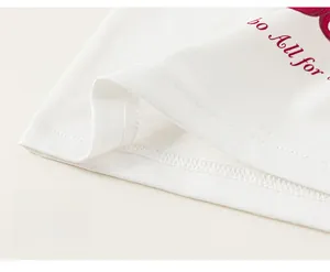 Détail de l'ourlet du débardeur blanc pour fille en coton avec impression rouge et couture