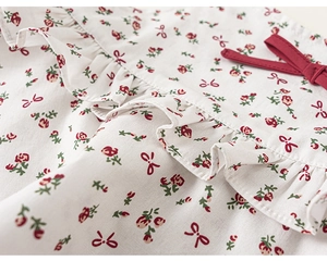 Detail of floral girls outfit showing red bows and ruffles on soft cotton fabric