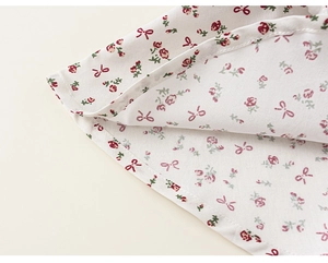 Detailed close-up of floral fabric with pink bows and fine hem stitching on girl's clothing