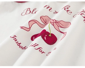 Détail macro du tissu en coton blanc côtelé avec motif de cerise rouge et nœud rose