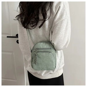 Détail montrant la texture en velours côtelé vert clair et les zips multicouches du sac