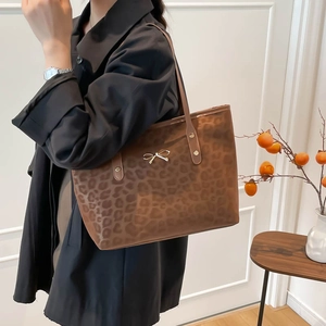 Stylish large leopard print tote bag with gold bow detail on a fashion model