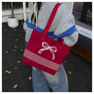 Outdoor shot of a red canvas tote bag with white bow pattern and twin handles