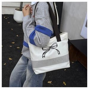 Detail of white canvas tote bag with black ribbon print and striped design for daily use