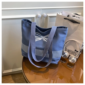 Close-up of deep blue canvas tote bag with white bow pattern on a vintage table