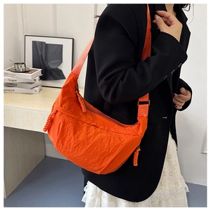 Detail of orange nylon crescent bag showing textured fabric and knotted zipper pull