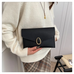 Detail of black cross-grain leather envelope clutch with golden oval metal lock