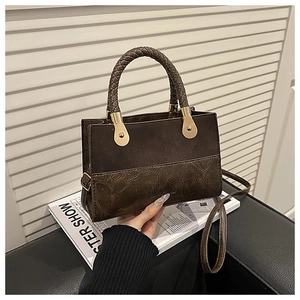 Detail of the woven handle and golden circular hardware on a brown patchwork handbag