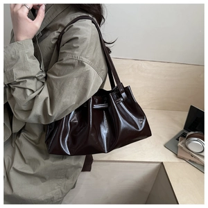 Detail view of dark brown patent leather tote bag with stylish pleated design and soft texture