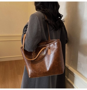 Macro view of brown vintage leather tote bag showing high-quality texture and gold lettering