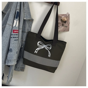 Detail of olive green canvas tote bag featuring a white bow print and thick double handles