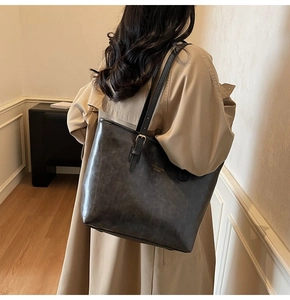 Detail view of a vintage charcoal leather tote bag with elegant thin adjustable shoulder straps