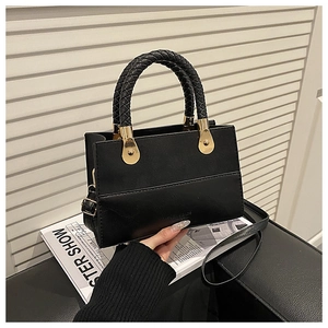Detail of black faux leather handbag featuring woven handles and gold teardrop hardware