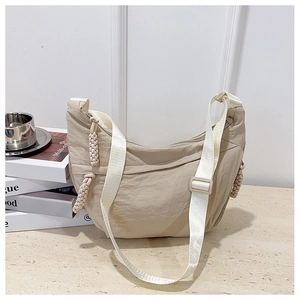 Dettaglio borsa a tracolla beige a mezzaluna con decoro in corda e ampia tracolla in tessuto