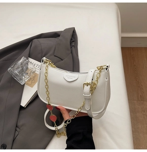Close-up of white lychee leather bag featuring gold chain and strawberry charm detail