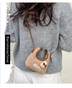 Détail du sac à bandoulière en peluche marron avec anse en cuir et breloque lapin blanc