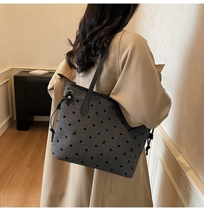 Detail of dark grey polka dot tote bag with bow accent on a model in trench coat