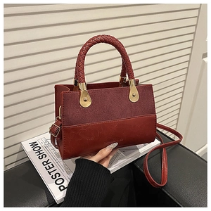 Detail of burgundy patchwork bag with suede finish, woven handle and gold metal hardware
