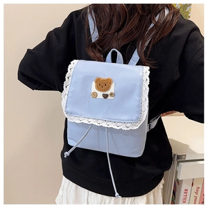 Close-up of a light blue backpack with lace trim and cute bear patch on a female model