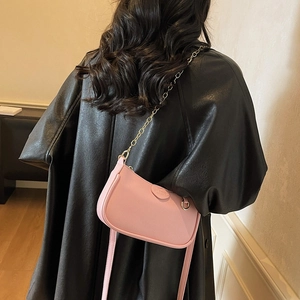 Pink crescent underarm bag with litchi grain leather and gold chain strap shown on model
