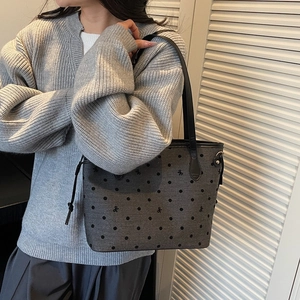 Gray polka dot tote bag with embroidered bow design and long black shoulder straps