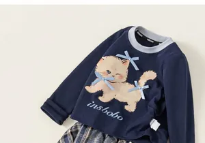 Dettaglio della felpa blu navy con gatto e fiocchi abbinata a gonna a quadri