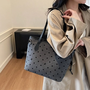 Grey tote bag with black polka dots and butterfly embroidery shown on model shoulder
