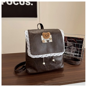 Macro detail of brown PU leather backpack with white lace edge and bear embroidery