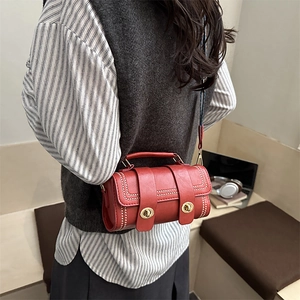 Deep red cylindrical vintage leather crossbody bag with dual metal buckles and stitching