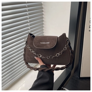 Détail du sac bandoulière en daim marron foncé avec chaîne à fleurs argentées et bandoulière tissée