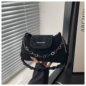 Détail du sac bandoulière en daim noir avec chaîne fleurie et bandoulière tissée