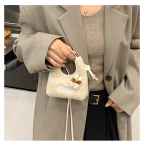 Dettaglio borsa in peluche bianco sporco con decoro coniglio 3D e ricamo Cutie su modella
