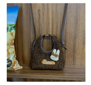 Dettaglio della borsa a tracolla in pile marrone con toppa a coniglio e ricamo colorato