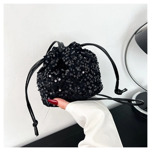 Détail d'un sac seau à paillettes noires avec cordon de serrage et bandoulière en cuir