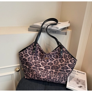 Close-up of leopard print tote bag with black leather straps and gold metal clasp closure