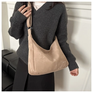 Detail view showing beige suede texture and minimalist branding on large crossbody bag