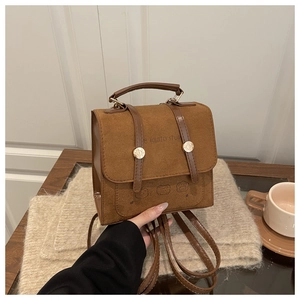 Close-up of vintage brown suede backpack with leather straps and gold metal buckle detail