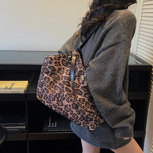 Chic leopard print tote bag with metal buckle shown on model in a modern interior setting