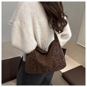 Detail of large brown leopard print tote bag styled as a shoulder bag on a model