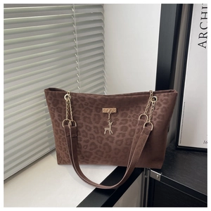 Close-up of leopard print tote bag with gold deer pendant and chain strap detail