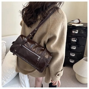 Detail of dark brown cylindrical crossbody bag with silver zipper in retro biker style